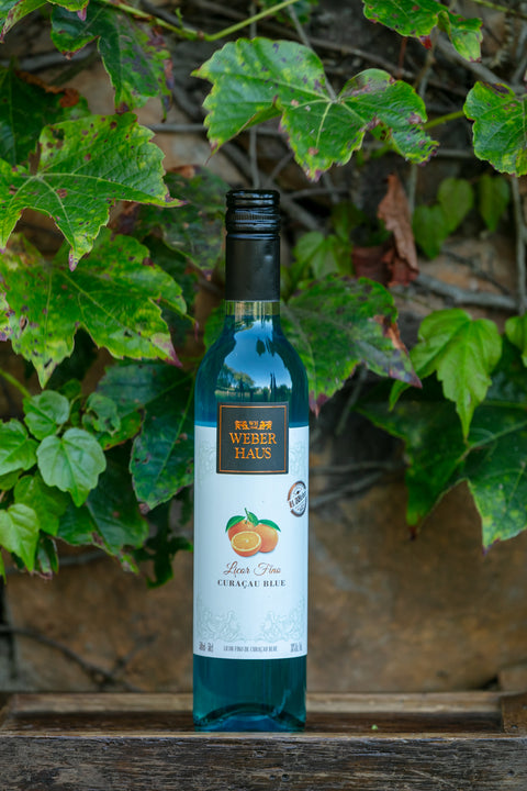 Garrafa de Licor Fino Weber Haus Curaçau Blue 500ml em ambiente externo.