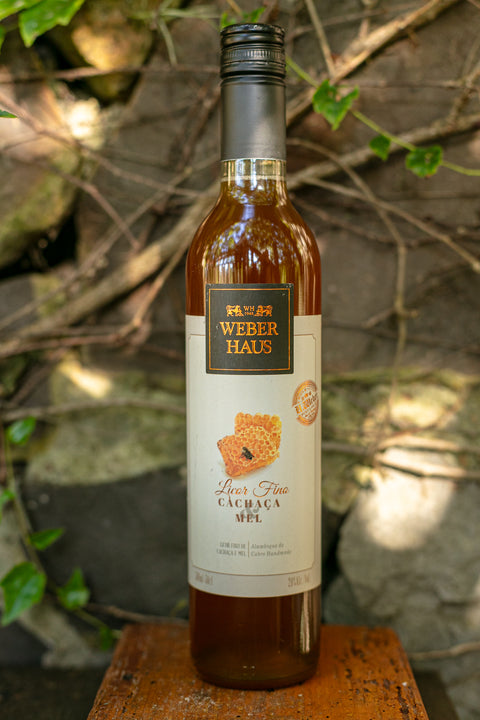 Garrafa de Licor Fino Weber Haus de Cachaça e Mel 500ml em ambiente externo.