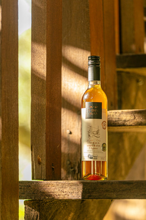 Garrafa de Licor Fino Weber Haus de Cachaça Amburana em ambiente externo.