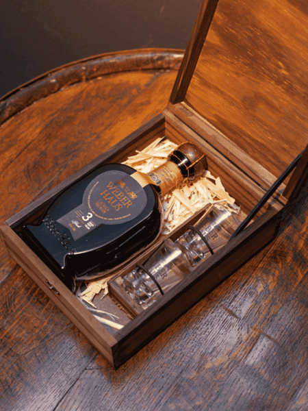 Estojo Weber Haus Black 3 Anos com garrafa de cachaça e dois copos de vidro, perfeito para degustação e presente elegante.