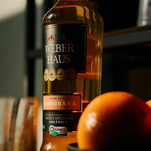 Cachaça ambientada com zoom no rotulo e laranja perto da camera