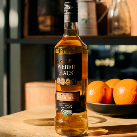 Cachaça Amburana Weber Haus em uma mesa ao lado de laranjas