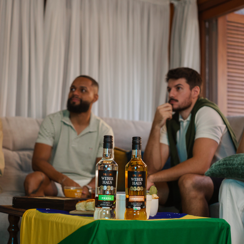 Dois homens olhando jogos com duas garrafas e cima de uma mesa na frente deles