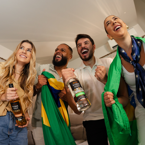 Grupo de pessoas comemorando jogos com duas garrafas na mão