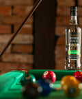 Garrafa de Cachaça Prata Weber Haus 700ml em cima de uma mesa de sinuca.