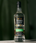 Cachaça Prata Weber Haus em cima de uma mesa e fundo verde