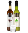 Licor de menta e de chocolate paradas uma do lado da outra com um copo de shot na frente em um fundo branco