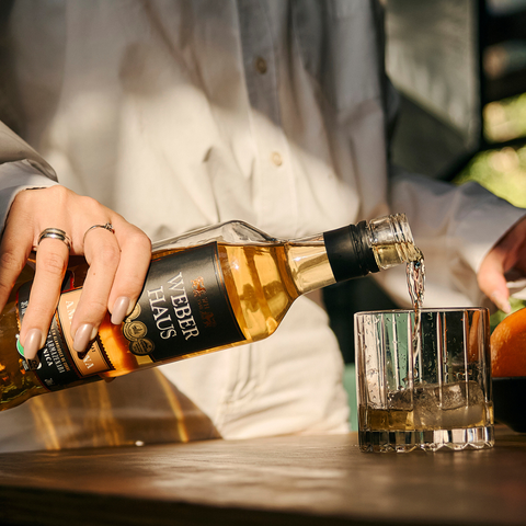 Cachaça sendo servida em um copo por uma mulher