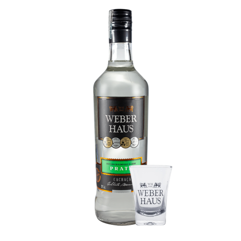 garrafa ao lado de um copo de shot em fundo branco