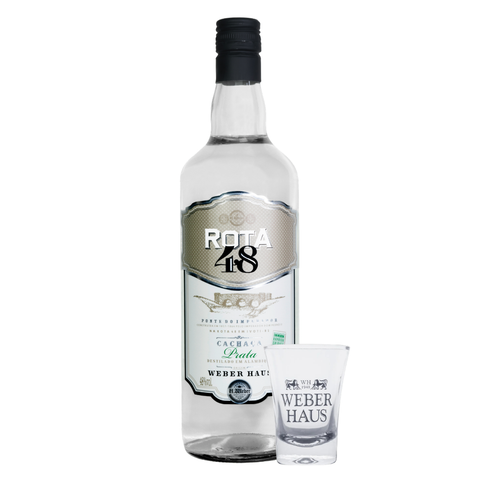 Garrafa ao lado de copo de shot em fundo branco