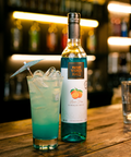 garrafa sobre o balcão de um bar com um drink ao lado